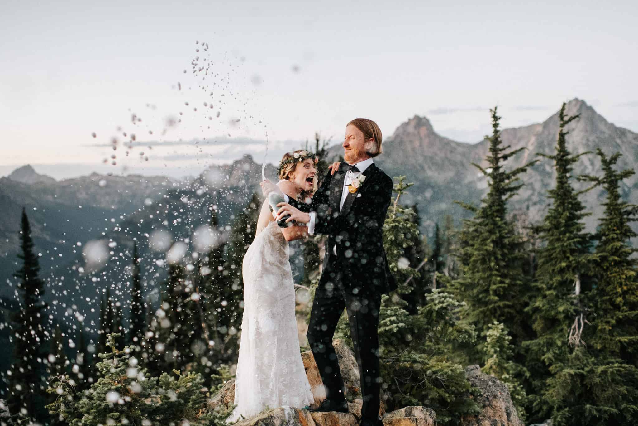 A wedding couple is standing on top of a mountain, one of the pictures that shows adventure elopements.