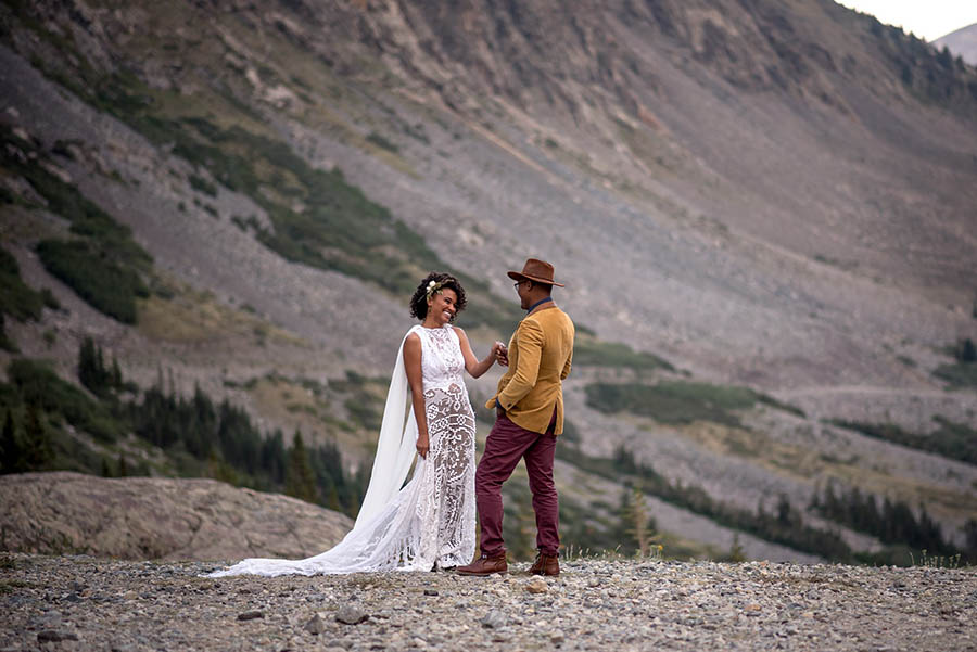 A wedding couple is holding hands and smiling at each other and are standing in Breckenridge.
