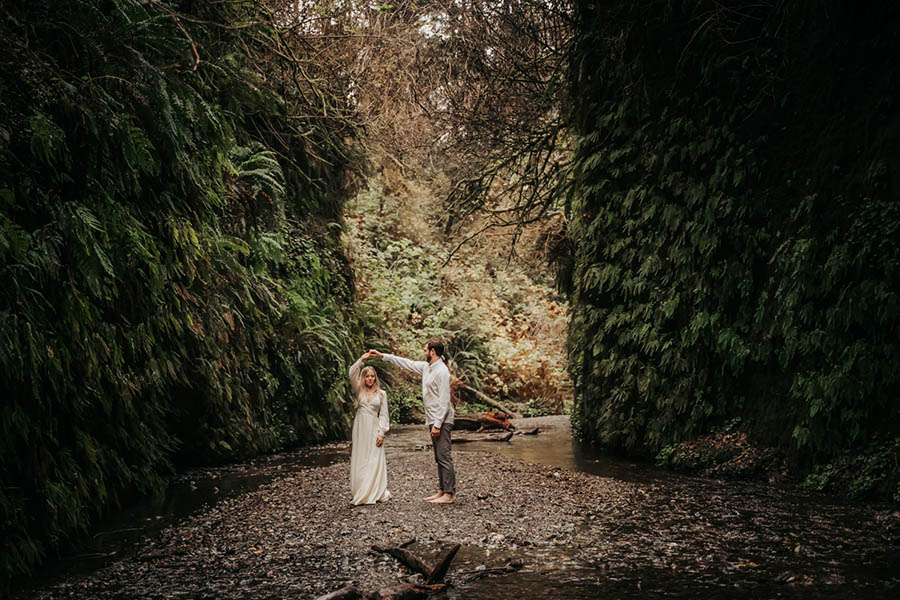 A wedding couple is dancing in the middle of the Fern Canyon in Northern California.