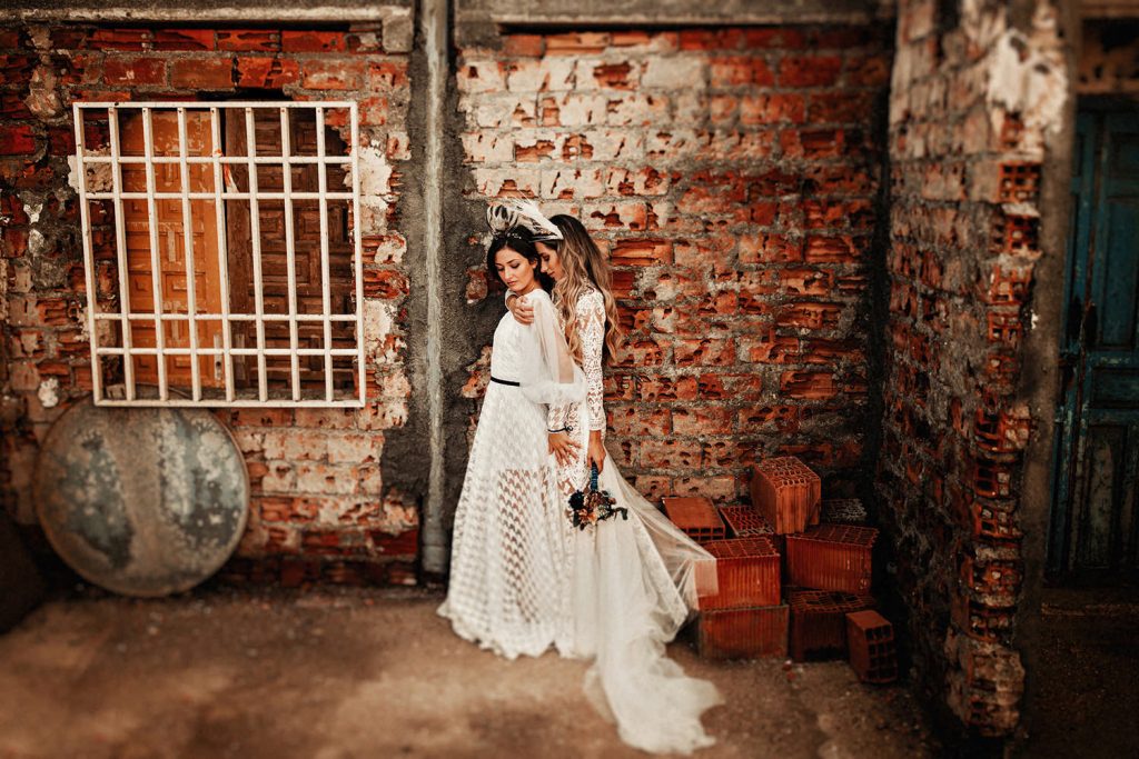 A wedding couple is holding each other and is standing in front of a brick wall, featured at the elopement checklist post.