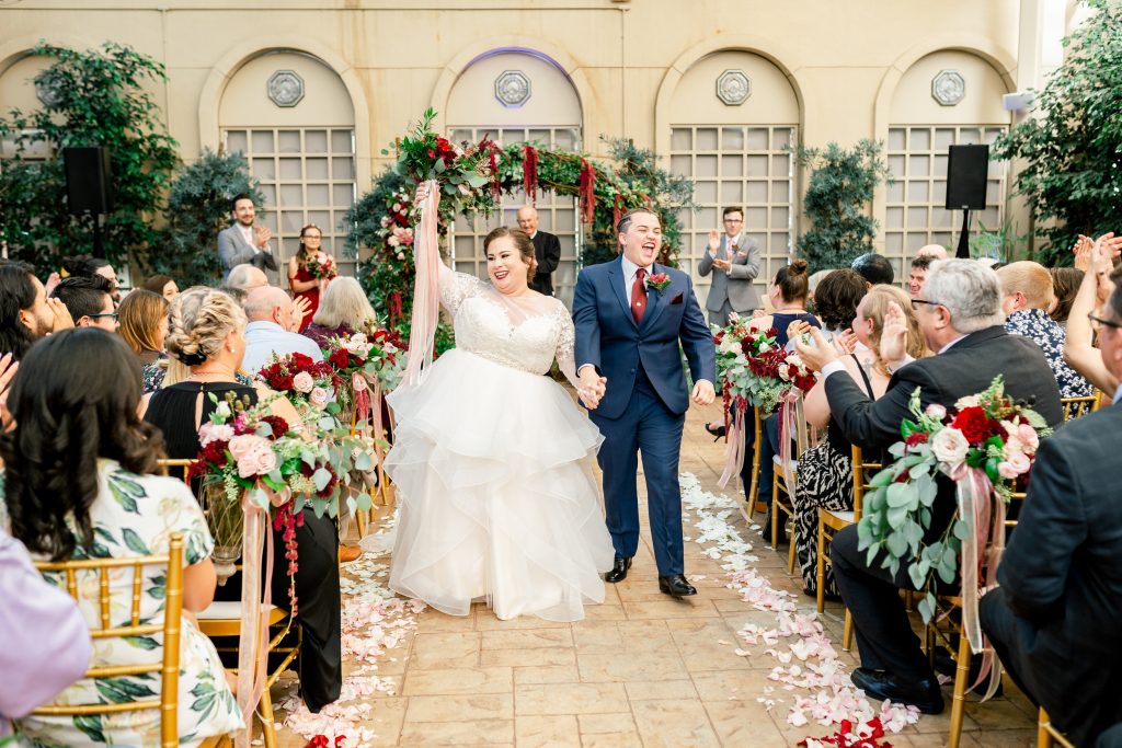 A wedding couple just got married and is cheering together with their guests at the Hotel De Anza, one of the wedding venues San Jose offers.
