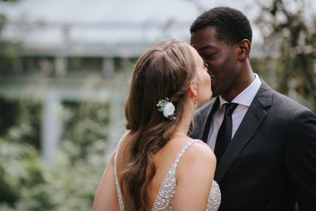 A couple is kissing at their Allan Gardens Conservatory Wedding