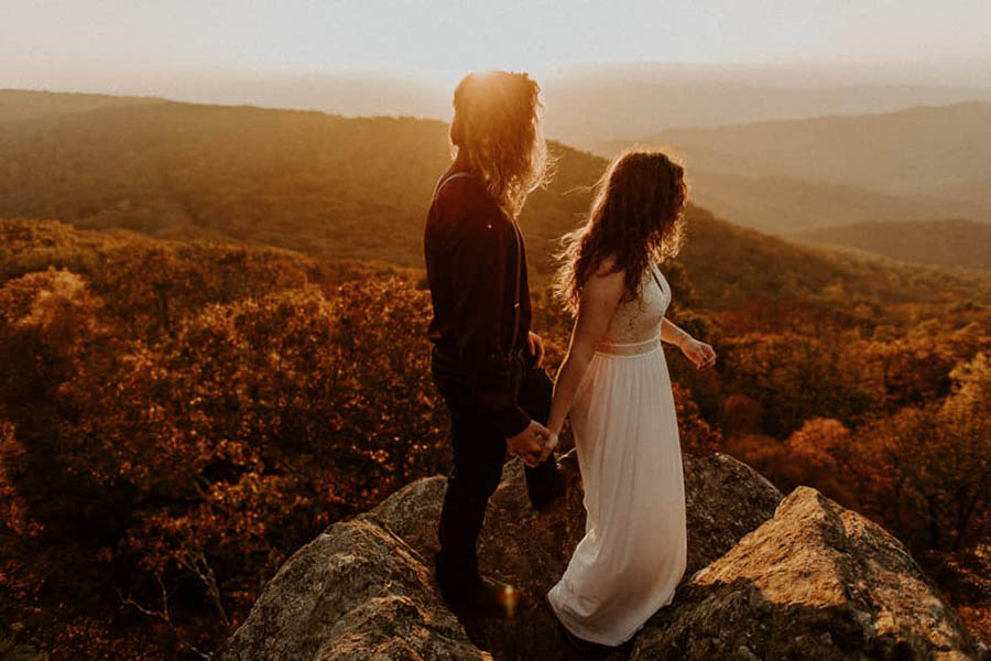 A wedding couple is holding hands and standing in the Shenandoah National Park in Virginia.