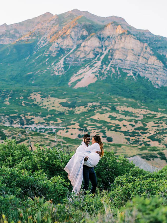 A groom is carrying his bride in the middle of a field near the Provo Canyon in Utah. 
