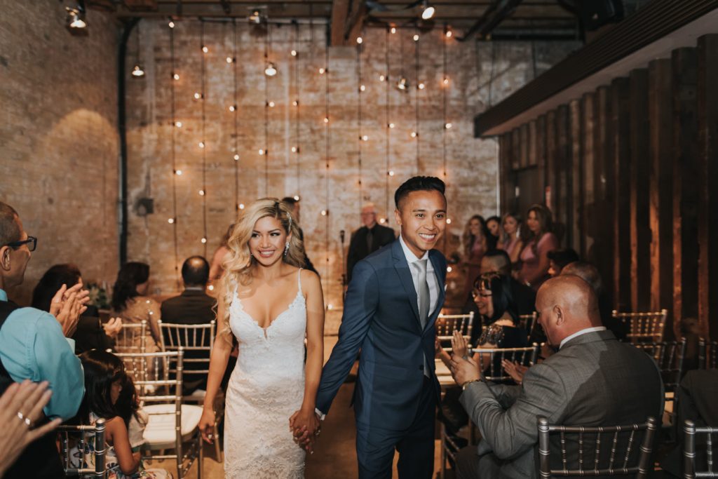 A wedding couple is walking back the aisle at the Distillery Loft, one of the wedding venues Toronto offers.