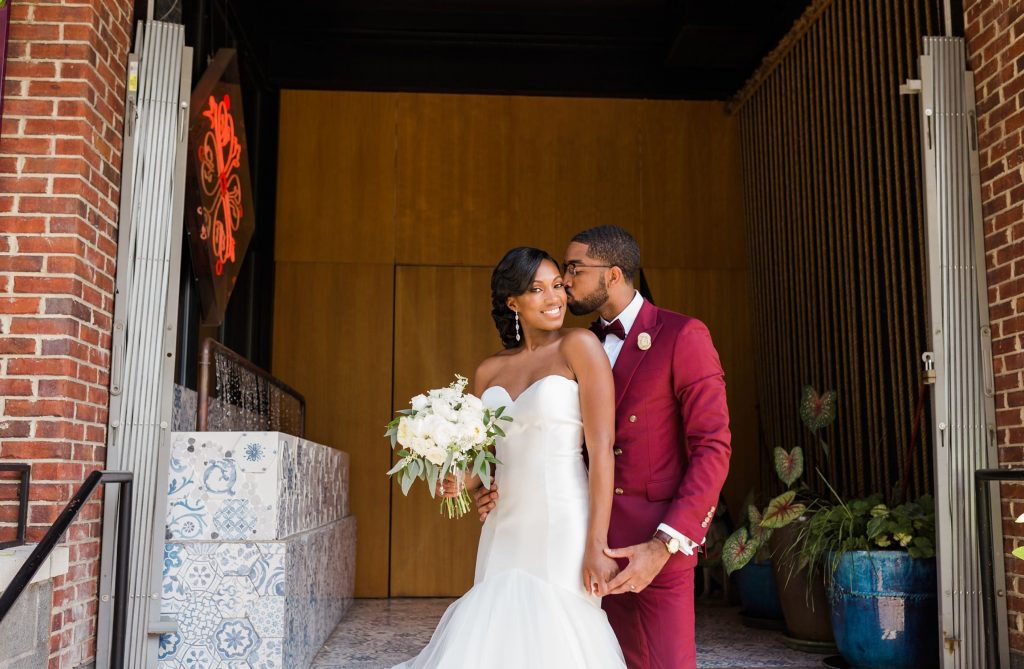 A wedding couple is standing outside of the Vidrio Raleigh, one of the wedding venues Raleigh NC offers.