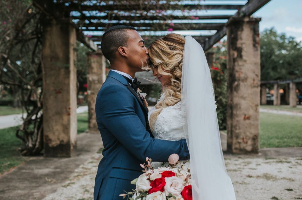 a groom is kissing his bride on her forehead at the Briza on the Bay, one of the Miami wedding venues.