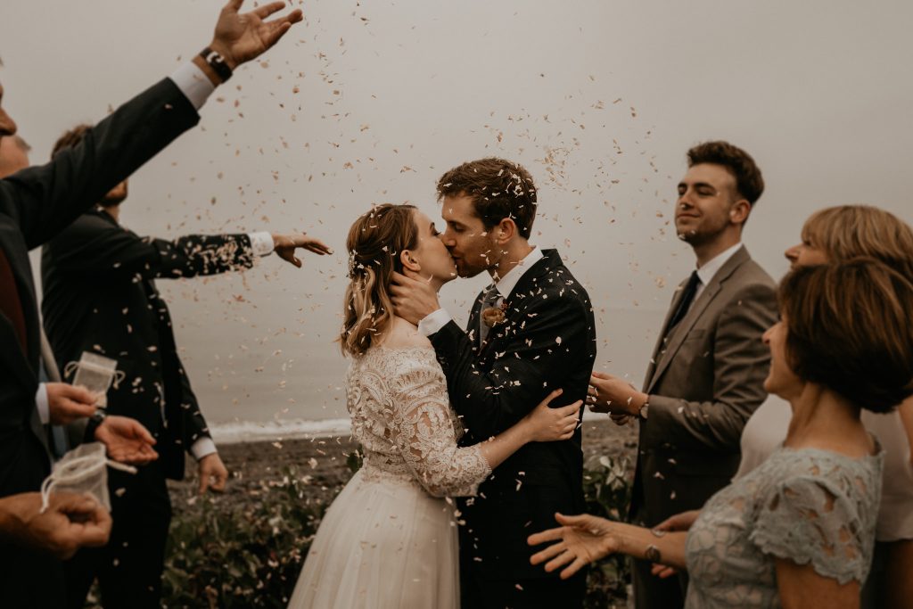 A wedding couple is kissing each other and their guests are cheering, photographed by a wedding photographer Seattle.