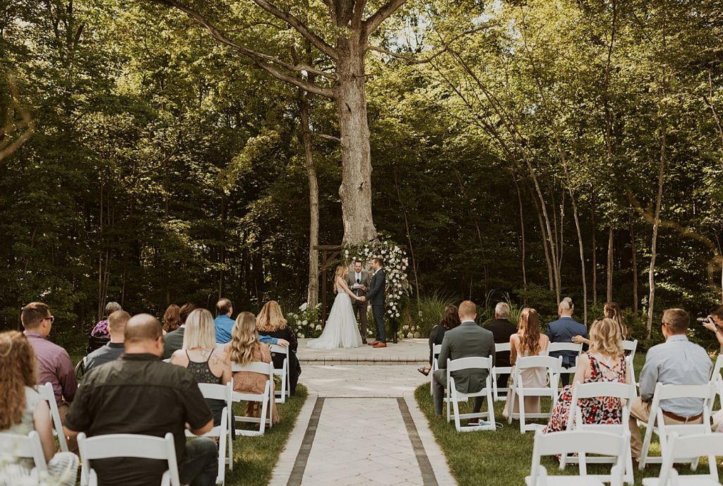 A wedding couple is getting married in front of a big tree at Crimson Lane, in Ohio.