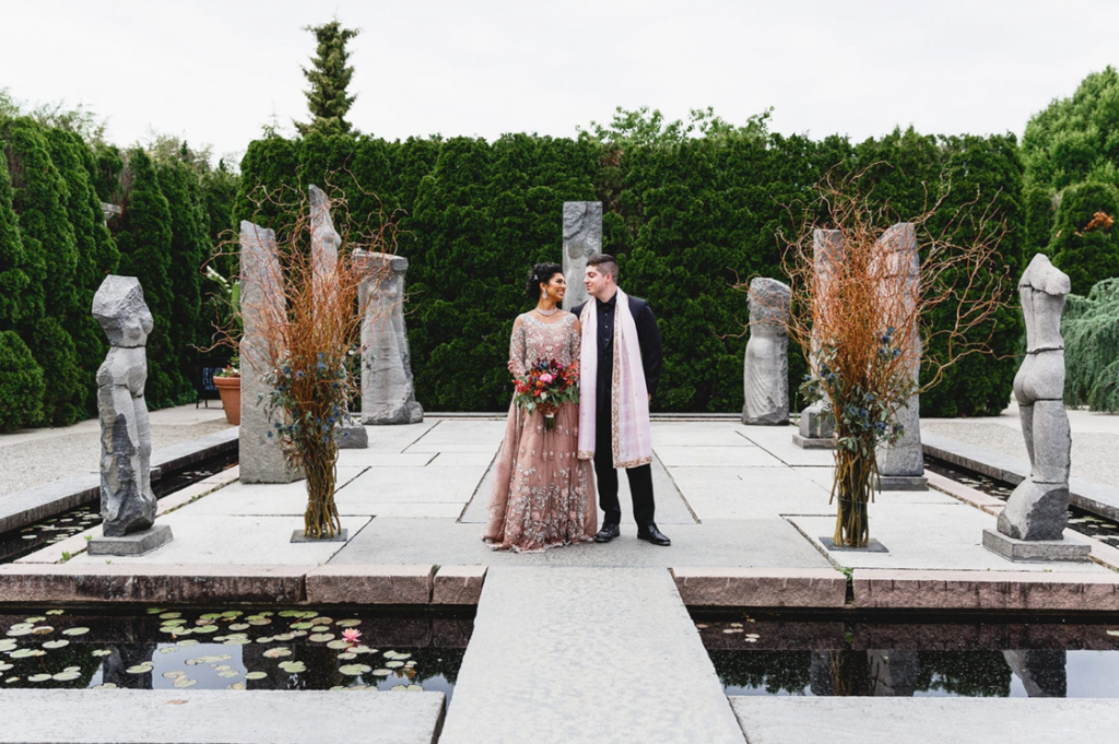 A wedding couple is standing at the Grounds of Sculpture, one of the New Jersey wedding venues.