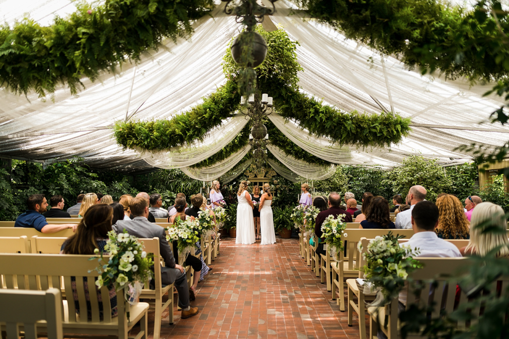 A wedding couple is standing at the end of the aisle at the Conservatory in Saint Charles, one of the wedding venues in Missouri.