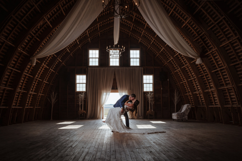 A wedding couple is kissing each other in a barn, one of the wedding venues in Delaware..