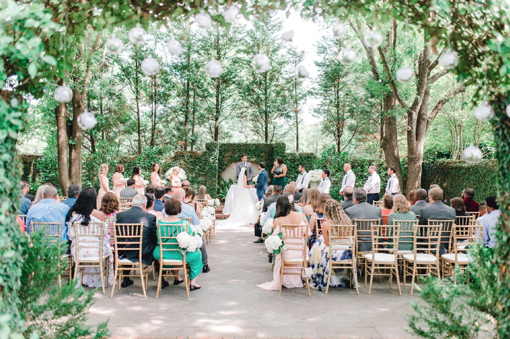 A wedding couple is standing at the altar and getting married, their guests are sitting in front of them.