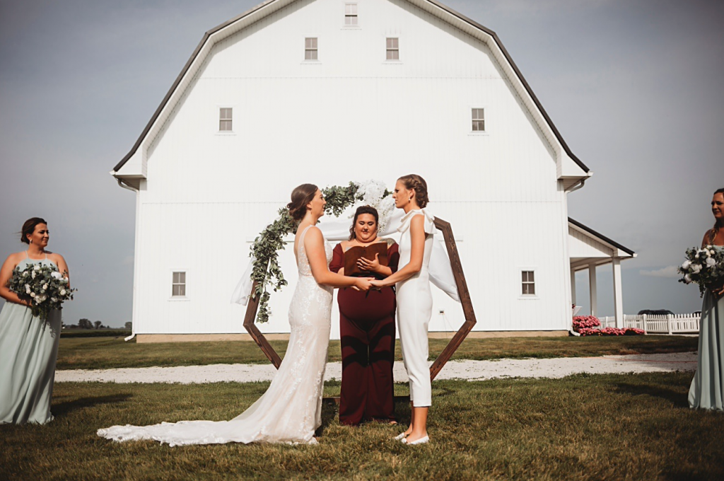 A wedding couple is getting married and standing at the altar in front of the Gathering Barn, one of the wedding venues in Indiana.