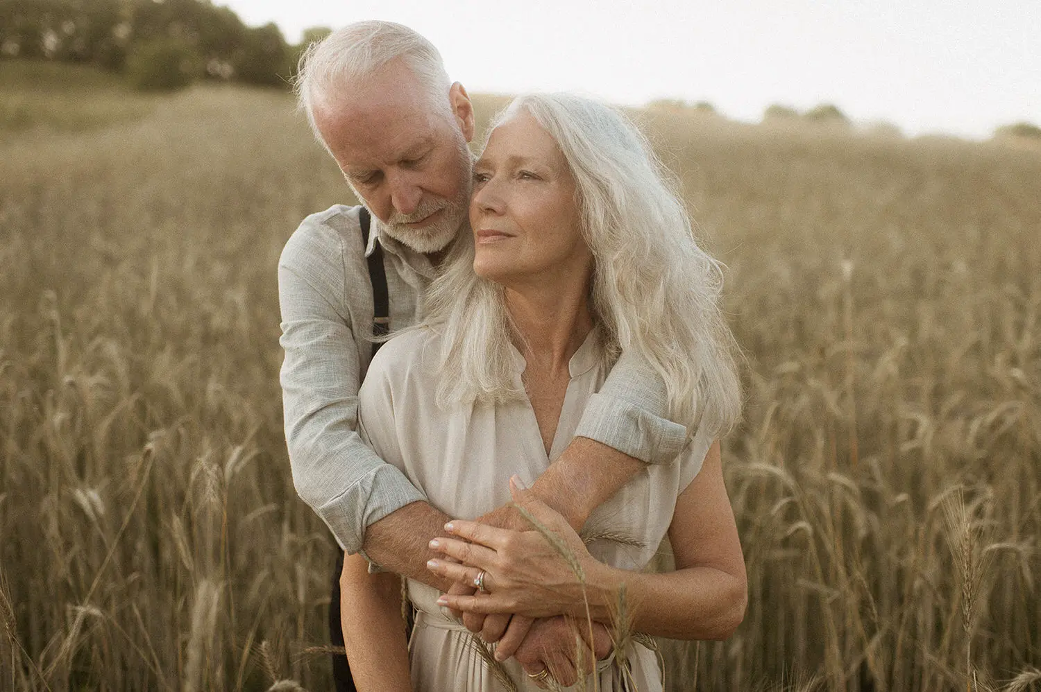 Elderly couple in an embrace among tall wheat, a serene and affectionate moment enhanced by nostalgic Lightroom presets