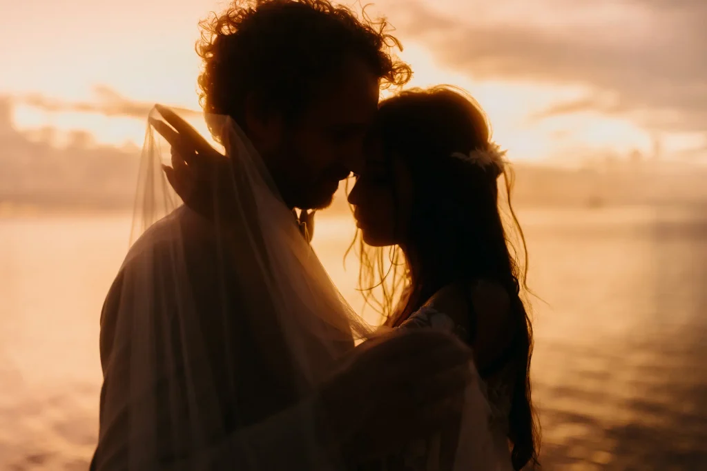 A couple sticks their heads together at sunset and thinks about how to plan a destination wedding.