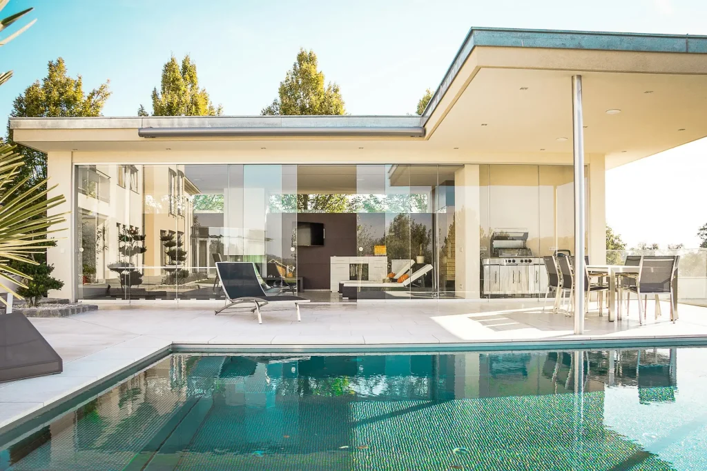 Luxury modern home with a swimming pool, outdoor lounge, and glass-walled living space. A great example of real estate photography tips, highlighting natural light, wide-angle composition, and clean staging for a professional property showcase.