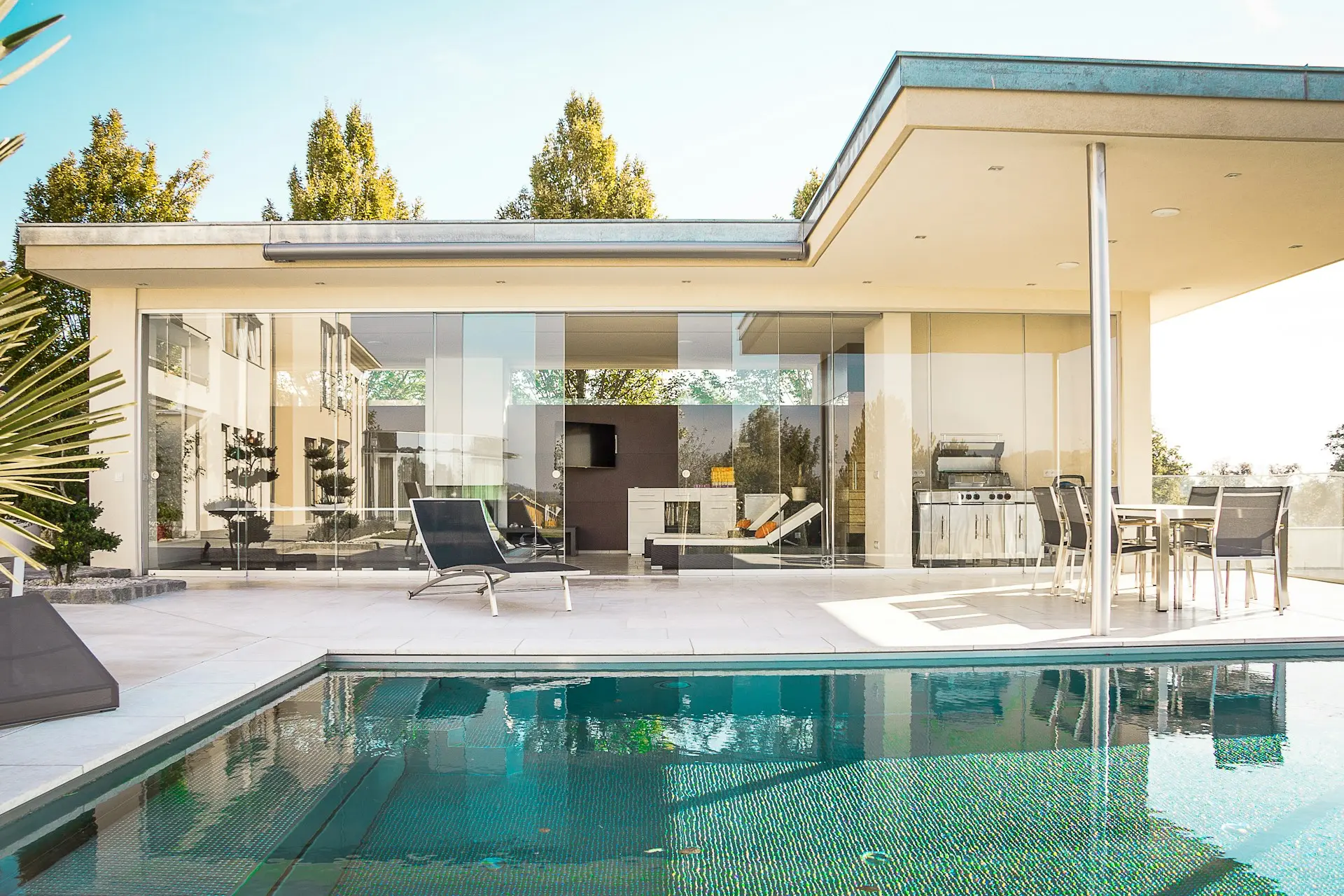 Luxury modern home with a swimming pool, outdoor lounge, and glass-walled living space. A great example of real estate photography tips, highlighting natural light, wide-angle composition, and clean staging for a professional property showcase.