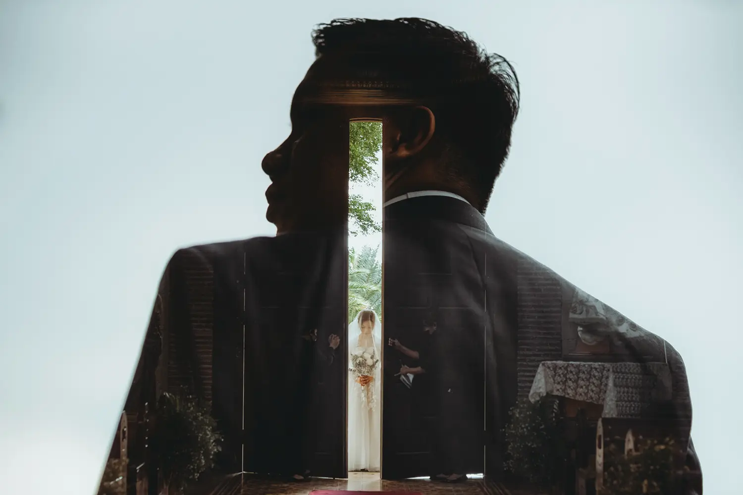 Artistic double exposure of a groom’s silhouette blended with an image of the bride entering through a doorway, symbolizing anticipation before the wedding ceremony.