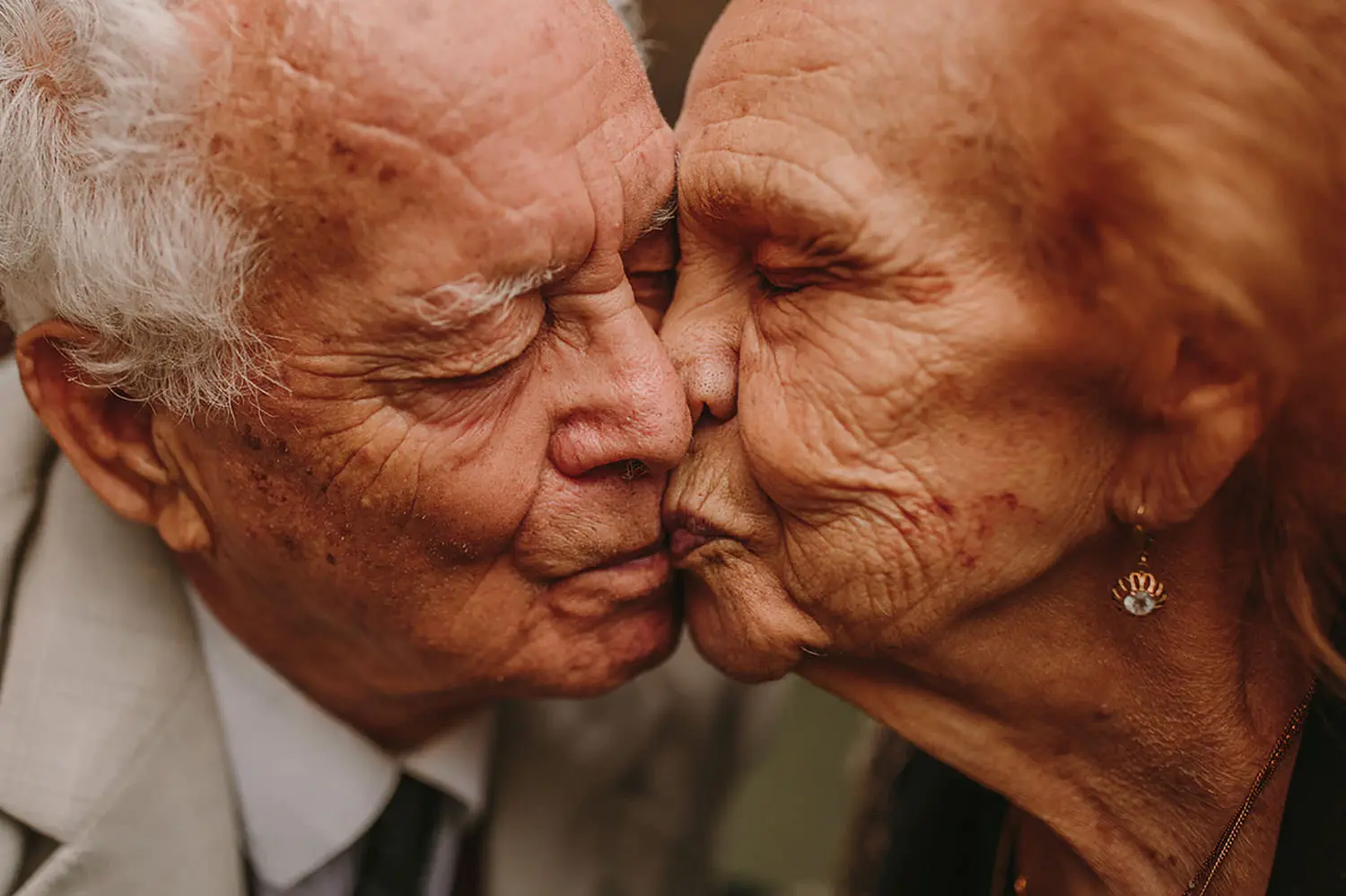 An elderly couple sharing a tender kiss, their faces close together, highlighting a lifetime of love and shared experiences.