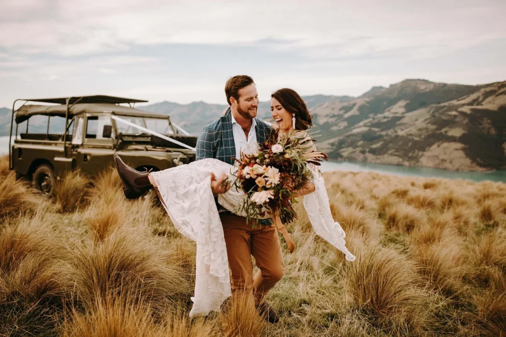 A groom carries his bride in his arms at their destination wedding in NZ.